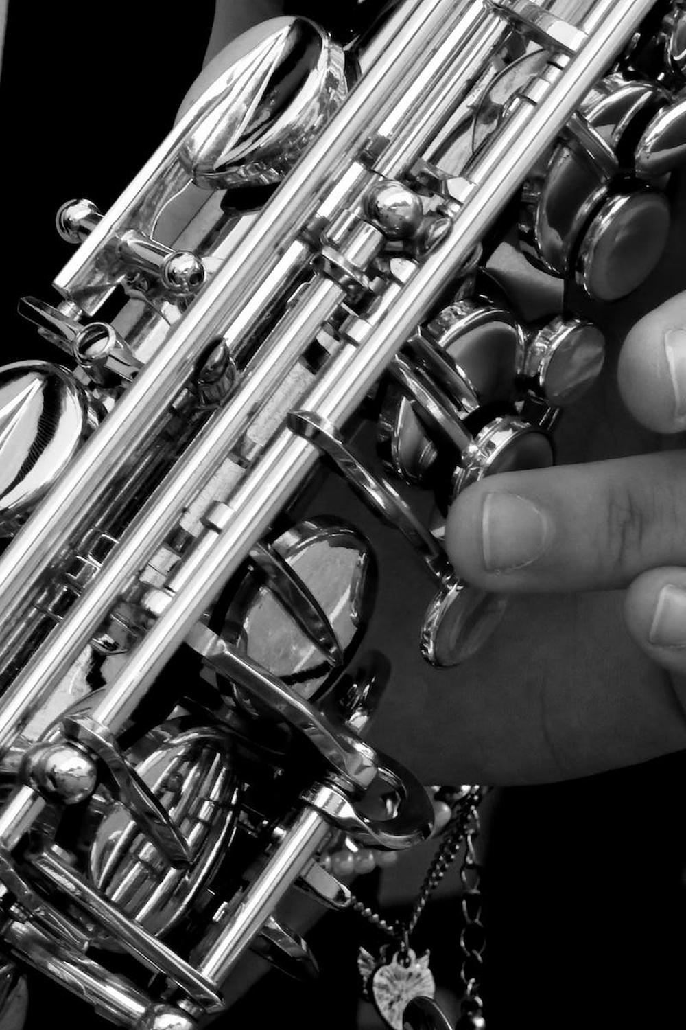 person_holding_saxophone_in_gray_scale_photography